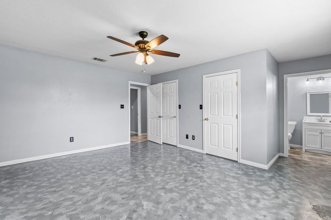 Unfurnished bedroom with connected bathroom, multiple closets, and a ceiling fan | Image 30