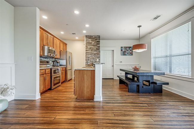 Kitchen featuring dark wood finished floors, a sink, visible vents, appliances with stainless steel finishes, and brown cabinets | Image 5