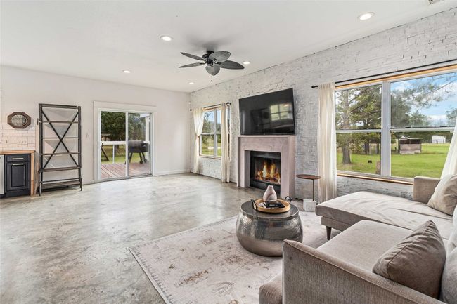 Living room featuring ceiling fan, a lit fireplace, recessed lighting, and finished concrete floors | Image 9
