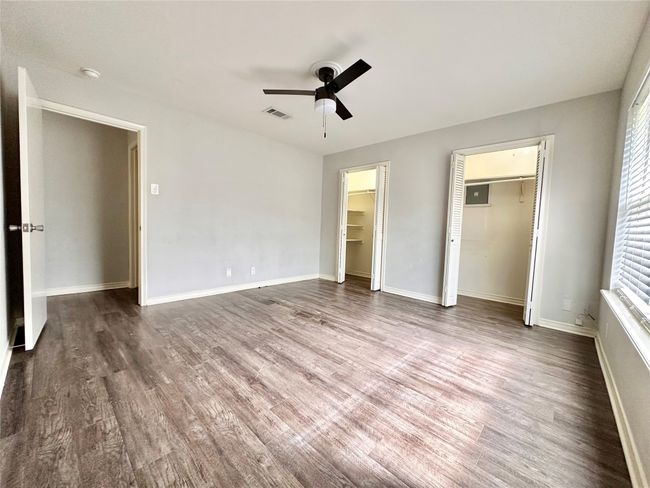 Unfurnished bedroom with wood finished floors, a ceiling fan, and multiple closets | Image 26