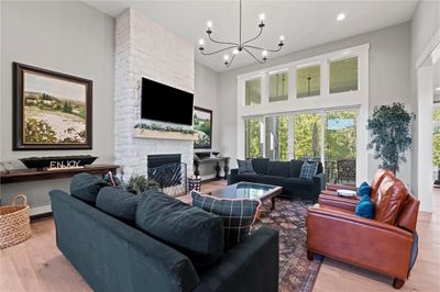 Living room featuring a towering ceiling, an inviting chandelier, light hardwood / wood-style floors, and a fireplace | Image 3