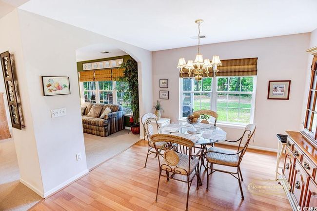 Dining room with arched walkways, light wood-style flooring, and a chandelier | Image 9
