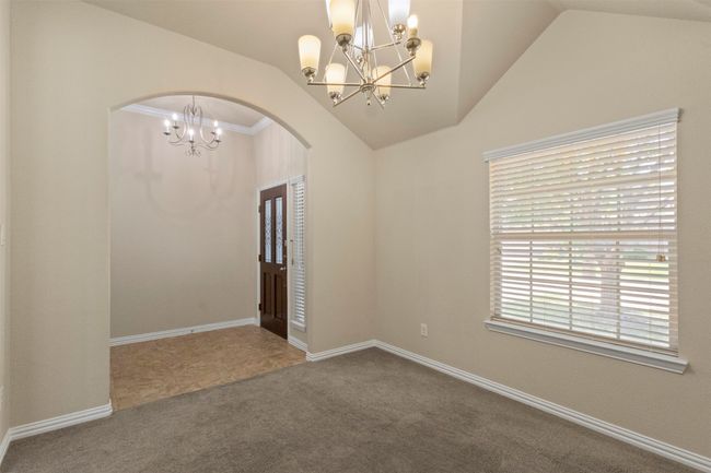 Empty room with a chandelier, arched walkways, lofted ceiling, and carpet floors | Image 8