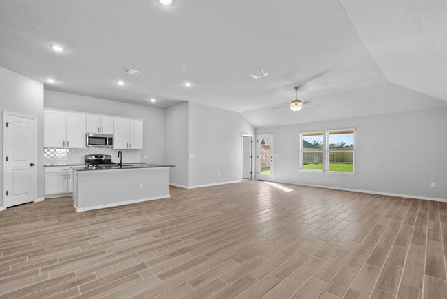 Kitchen with open floor plan, appliances with stainless steel finishes, baseboards, and lofted ceiling | Image 4