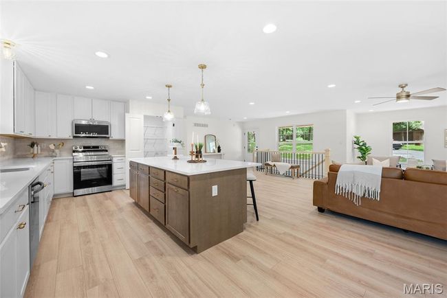 Kitchen with stainless steel appliances, recessed lighting, light wood-style floors, white cabinets, and light countertops | Image 17