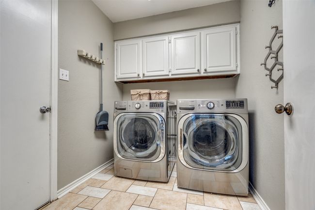 Laundry area with cabinet space, baseboards, and light tile patterned flooring | Image 30
