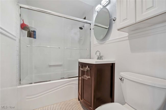 Bathroom with vanity, toilet, tile patterned flooring, and shower / bath combination with glass door | Image 21