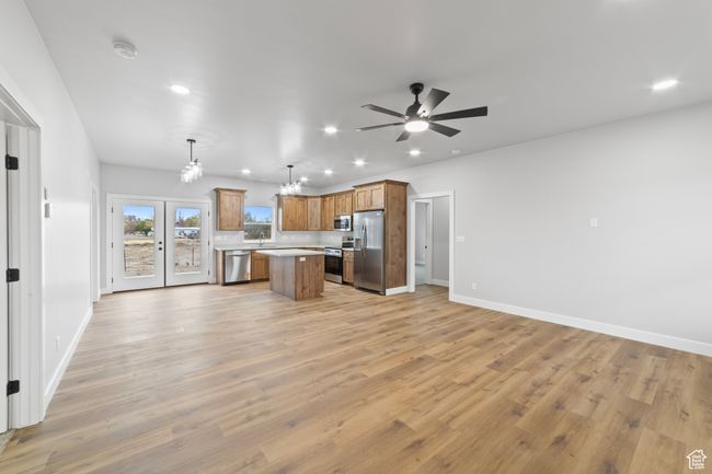 Kitchen with light countertops, open floor plan, light wood-type flooring, stainless steel appliances, and ceiling fan with notable chandelier | Image 6