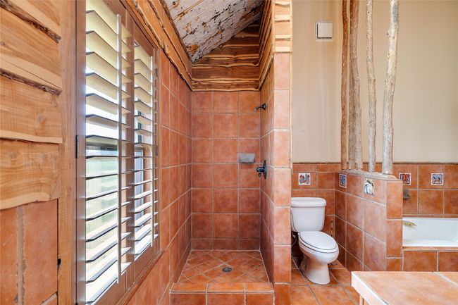 Full bath featuring toilet, vaulted ceiling, tiled shower, a bathtub, and tile patterned flooring | Image 14