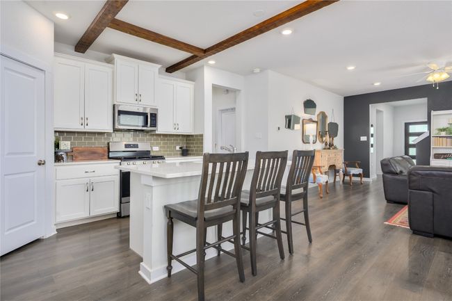 Kitchen with stainless steel appliances, tasteful backsplash, light countertops, open floor plan, and dark wood-style flooring | Image 4