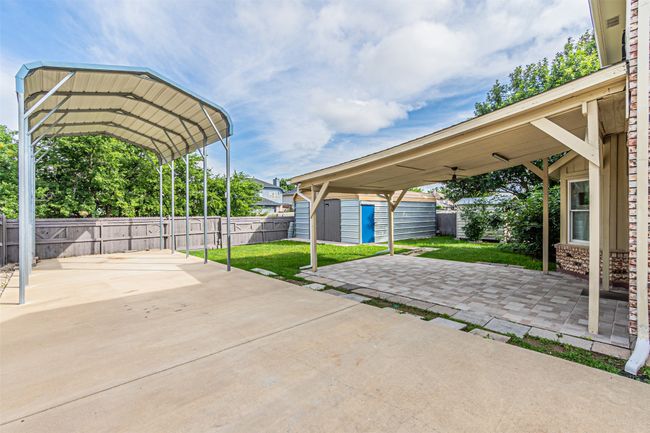 Fenced backyard featuring a storage shed and a carport | Image 31