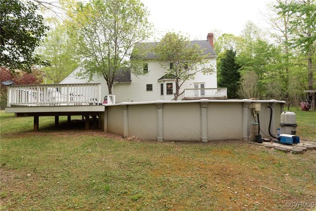 Back of house featuring a chimney, an outdoor pool, a yard, and a deck | Image 10