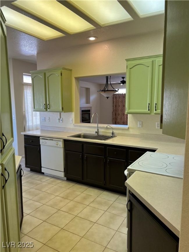 Kitchen featuring dishwasher, a sink, green cabinets, light countertops, and light tile patterned floors | Image 12
