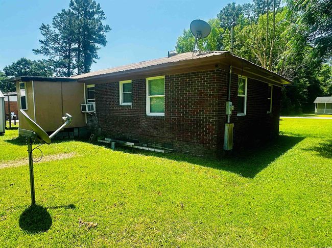 View of side of property featuring brick siding, a lawn, and metal roof | Image 23
