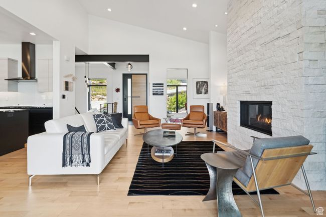 Living room featuring a stone fireplace, high vaulted ceiling, light wood-style flooring, and recessed lighting | Image 40