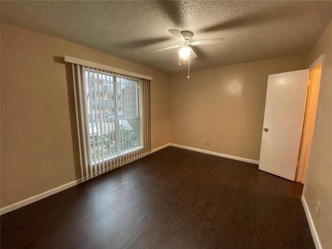 Spare room featuring a ceiling fan, dark wood-style flooring, a textured ceiling, and baseboards | Image 18