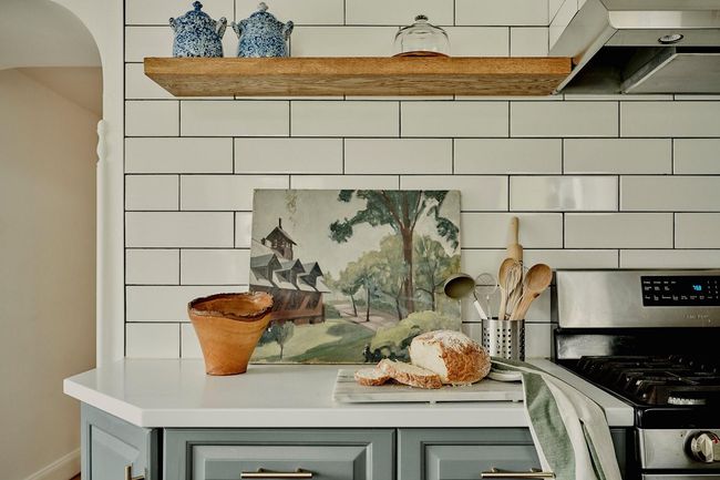 Kitchen view of stainless steel gas stove, extractor fan, arched walkways, light countertops, and gray cabinetry | Image 7