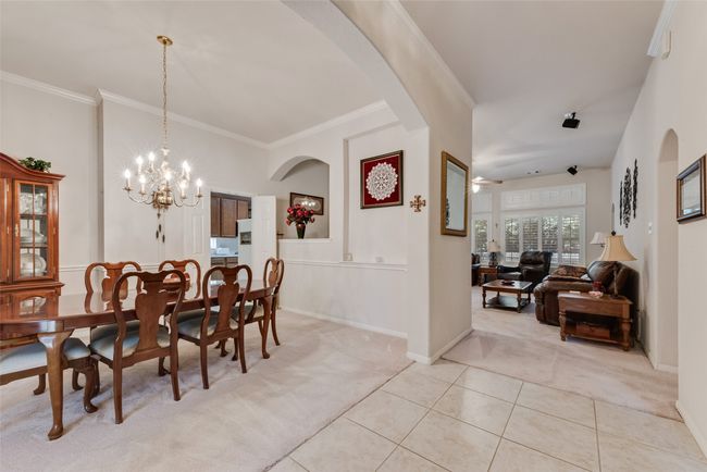 Dining space with light carpet, arched walkways, a chandelier, baseboards, and ornamental molding | Image 19