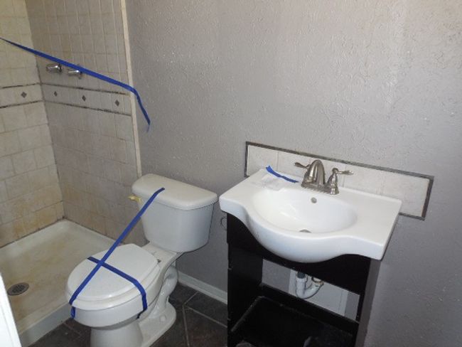 Full bath with a sink, toilet, a textured wall, tile patterned flooring, and a stall shower | Image 6