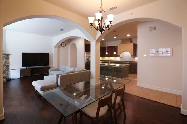Dining space with arched walkways, a notable chandelier, visible vents, and wood finished floors | Image 7
