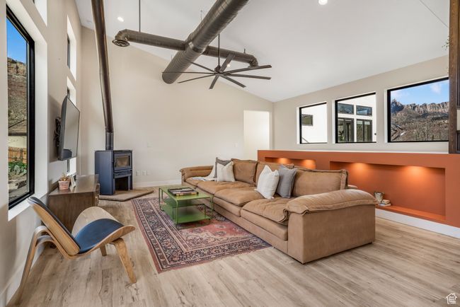 Living room featuring wood finished floors, a wood stove, baseboards, and a ceiling fan | Image 17