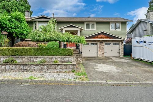 Two-story dwelling with green siding, a two-car garage, and stone-clad accents | Card Image
