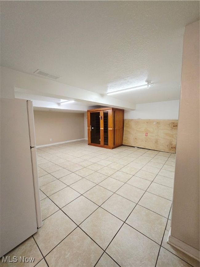 Finished below grade area featuring refrigerator and light tile patterned floors | Image 21