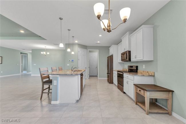 Kitchen featuring recessed lighting, white cabinetry, an inviting chandelier, and appliances with stainless steel finishes | Image 23