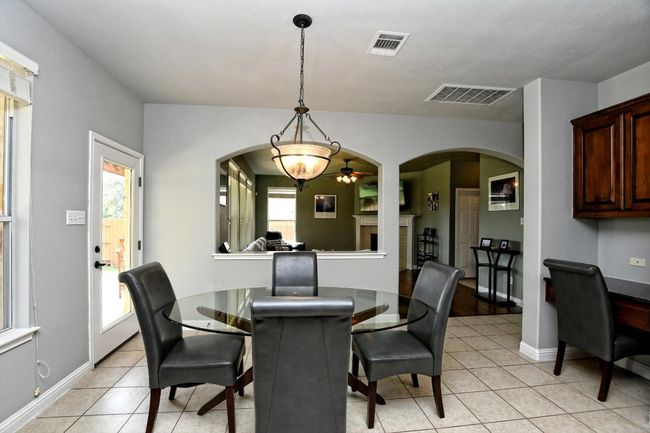 Dining room with arched walkways, light tile patterned floors, and a ceiling fan | Image 8