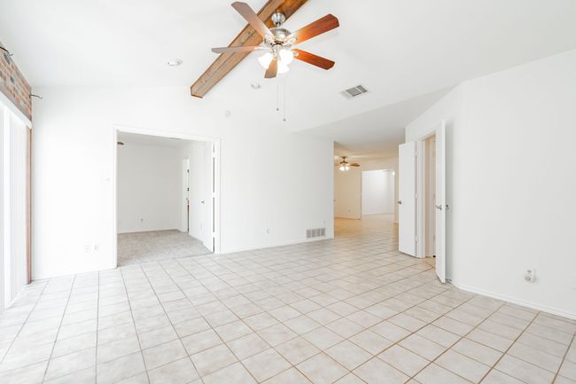 Unfurnished room featuring vaulted ceiling with beams, light tile patterned flooring, a ceiling fan, and visible vents | Image 16