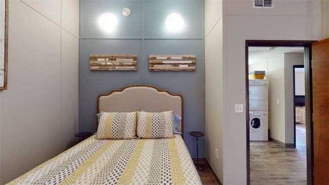 Bedroom with stacked washer / drying machine and wood finished floors | Image 31