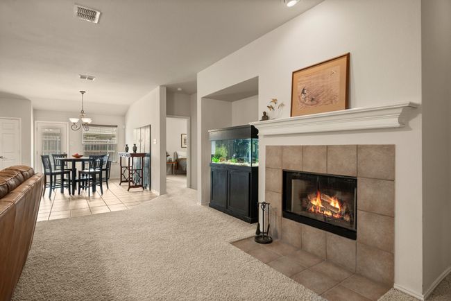 Bright and open floor plan connects the living room, kitchen, and dining areas. Includes a cozy fireplace, ceiling fan, and plenty of natural light from multiple windows. | Image 11