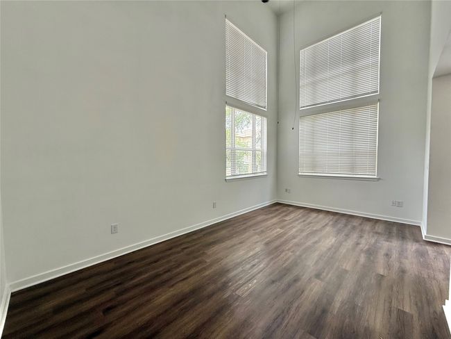 Empty room featuring dark wood-type flooring, baseboards, and a towering ceiling | Image 18