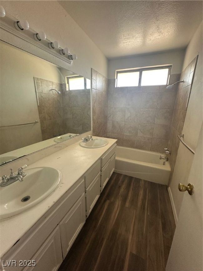 Full bath featuring wood finished floors, bathtub / shower combination, double vanity, and a textured ceiling | Image 12