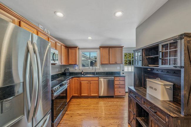 Kitchen with dark stone countertops, sink, light hardwood / wood-style flooring, and appliances with stainless steel finishes | Image 8