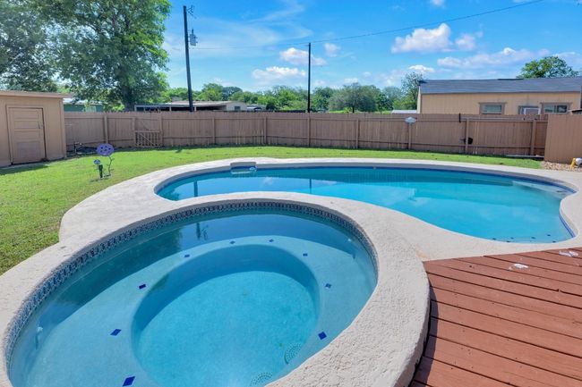 View of swimming pool featuring a fenced backyard and an in-ground hot tub | Image 31