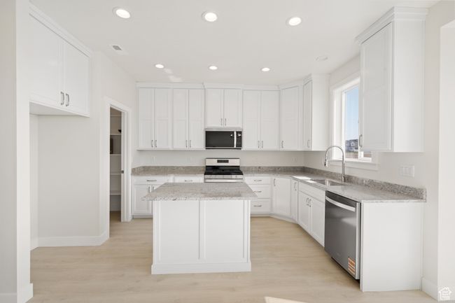 Kitchen with stainless steel appliances, white cabinetry, recessed lighting, a kitchen island, and light wood-type flooring | Image 6