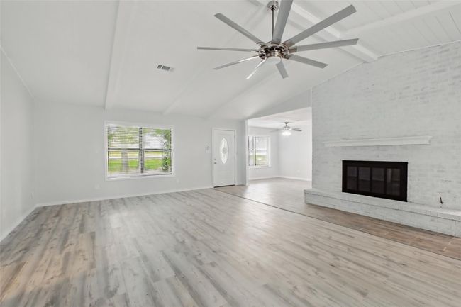 Vaulted ceilings and a white brick fireplace set the tone for this bright, inviting living room—perfect for both cozy nights in and casual entertaining. | Image 13