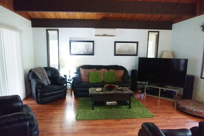 Living room featuring wood ceiling, a wall unit AC, beam ceiling, and wood finished floors | Image 19