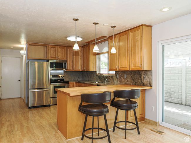 Kitchen featuring appliances with stainless steel finishes, wooden counters, a sink, and light wood-style flooring | Image 8