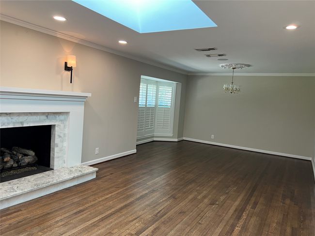 Unfurnished living room with crown molding, dark wood-style floors, a skylight, a premium fireplace, and recessed​​‌​​​​‌​​‌‌​‌‌​​​‌‌​​‌‌​‌​​​​​‌ lighting | Image 7