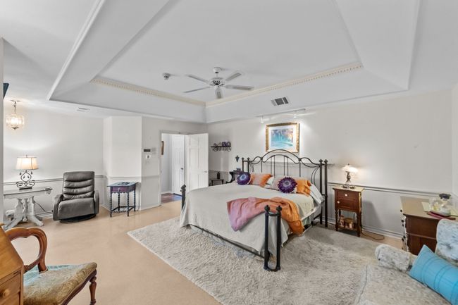 Bedroom with a raised ceiling, baseboards, ceiling fan, and visible vents | Image 17