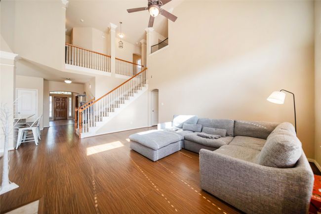 Living room featuring stairs, high vaulted ceiling, wood finished floors, and a ceiling fan | Image 16