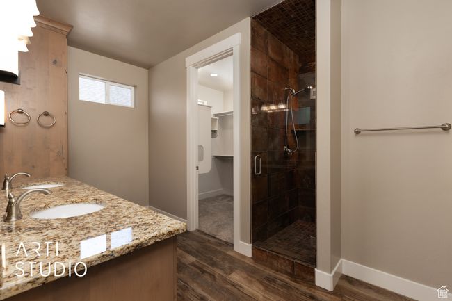 Bathroom featuring wood finished floors, a shower stall, double vanity, and a walk in closet | Image 24