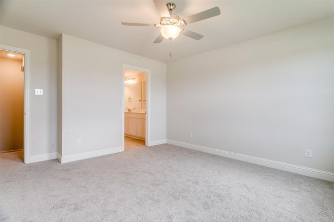 Unfurnished bedroom featuring light carpet, ensuite bath, and ceiling fan | Image 17