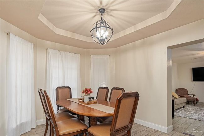 Dining area with a raised ceiling, a chandelier, wood finish floors, and baseboards | Image 7