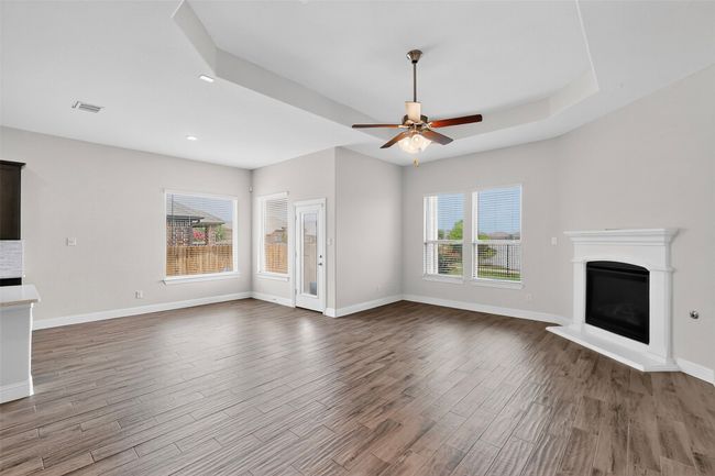 Unfurnished living room featuring a fireplace, a ceiling fan, wood finished floors, recessed lighting, and a raised ceiling | Image 13