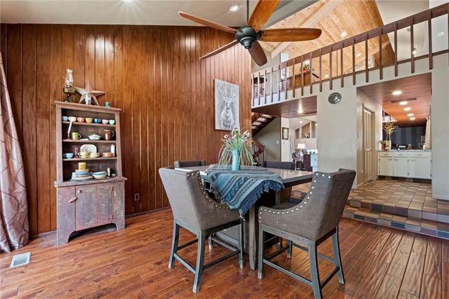Dining room with wood-type flooring, ceiling fan, stairs, and wood walls | Image 14