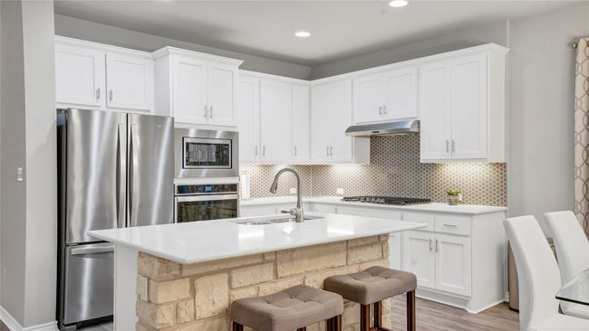 Kitchen with light countertops, under cabinet range hood, a sink, backsplash, and stainless steel appliances | Image 6