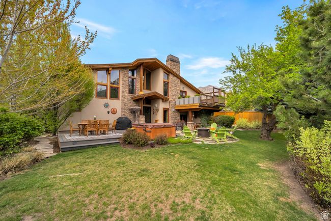 Back of house with a wooden deck, a chimney, a hot tub, stucco siding, and a yard | Image 39